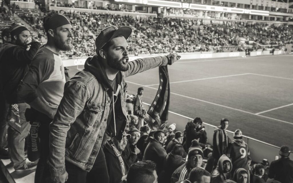 Free Monochrome Photo of Man Wearing Jacket Pointing Finger at Stadium Stock Photo